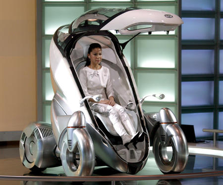 A Taiwanese show promoter demonstrates a Toyota PM electric vehicle at a press preview for the 2004 Taipei International Auto Show, Taipei on January 2, 2004.